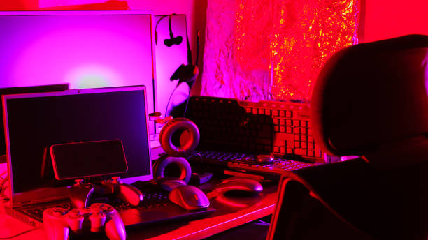 istock Gamer's workspace. Gamepads, computer mouse, headphones, keyboard and laptop on the table. Gaming accessories and computer equipment in neon light. Gambling addiction concept 1399784264