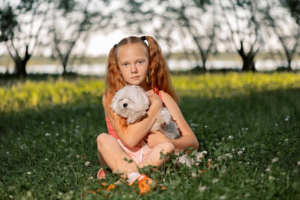 Girl with dog sitting on grass.