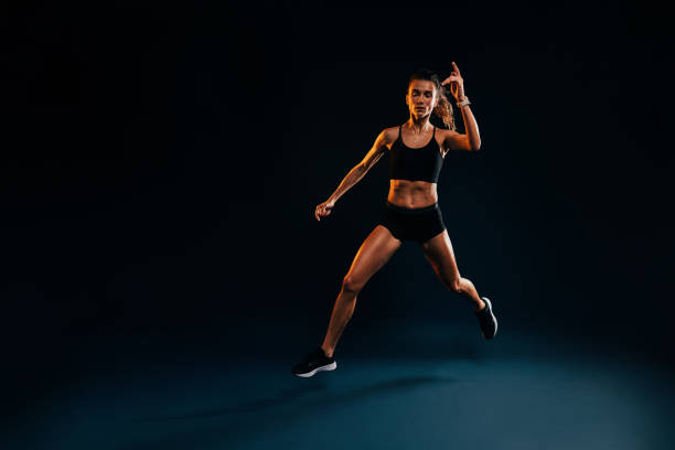 istock Young woman runner jumping in studio. Muscular athlete exercising on black backdrop. 1399796090
