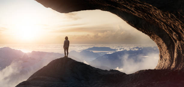 istock Dramatic Adventurous Scene with Woman standing inside a Rocky Cave Landscape 1399797314