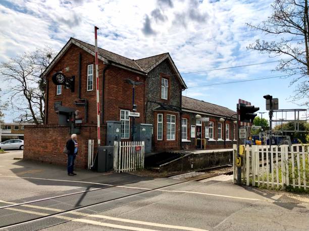 Facade of Cookham train station. Brick wall, cloud sky, small platform, local train line. Unrecognizable man. Great Western Railway