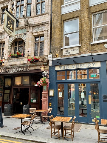 Street view of Barbican area in City of London. Fragment of Charterhouse street with “Fox and Anchor” pub and “The Vestry” cocktail bar. Selective focus. Vertical