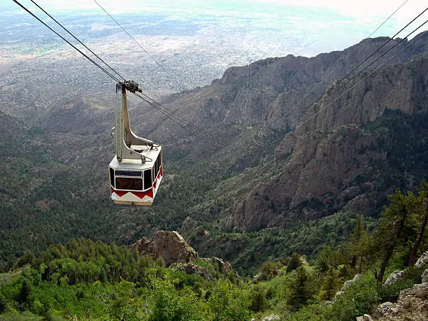 Photo of cable car approaching the top of Sandia Mountain in New Mexico.  The city of Albuquerque can be seen in the distance.