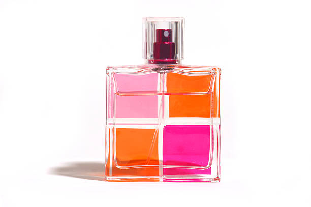 An open bottle of a golden perfume with the top placed on the side. Seamless grey and white background