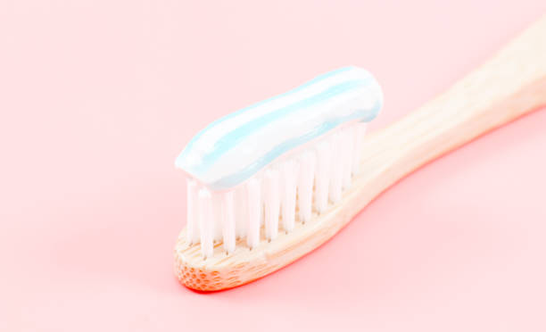 istock Bamboo toothbrush with toothpaste on the right on a soft pink 1399802997