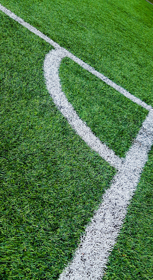 Close-up of a synthetic football pitch, shot from the sideways corner angle.