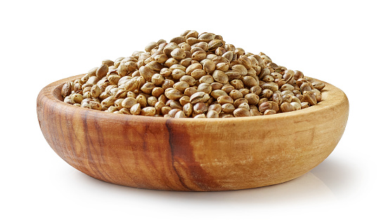 hemp seeds in olive wood bowl isolated on white background