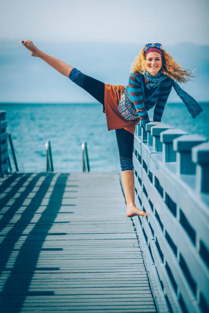 Happy beautiful woman stretching legs at pier.