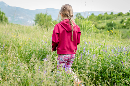 Happy little girl hiking through green fields