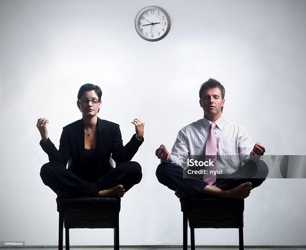 Two business people meditating during their break  Young business people in an abstract office enviroment are sitting in yoga lotus-pose and relaxing. 25-29 Years Stock Photo