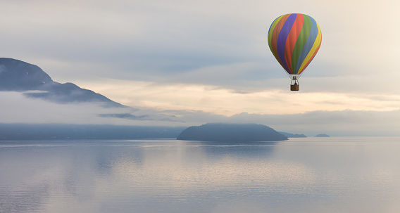 Hot Air Balloon flying over Canadian Mountain Nature Landscape on the Pacific West Coast. Cloudy and fog Winter Day. 3d Rendering aircraft Adventure Concept. Howe Sound, British Columbia, Canada.