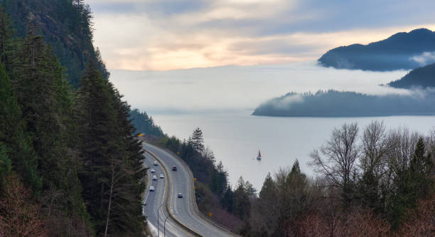 sea to sky highway con auto e howe sound in sottofondo coperto di nebbia e nuvole. - sea to sky highway foto e immagini stock