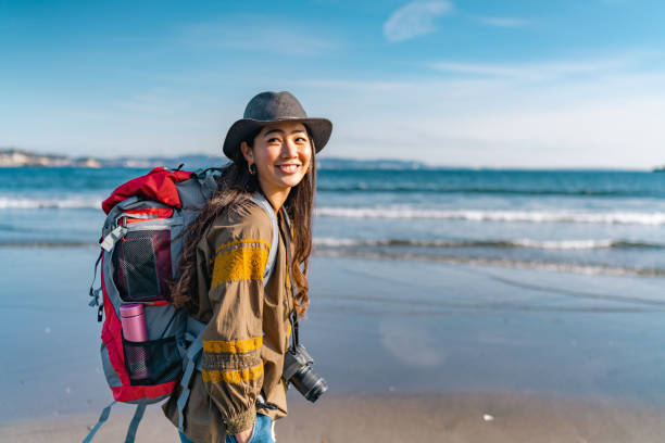 Young female traveller enjoying spending time at beach on her vacation A young female traveller is enjoying spending time at the beach on her vacation. asian tourist stock pictures, royalty-free photos & images