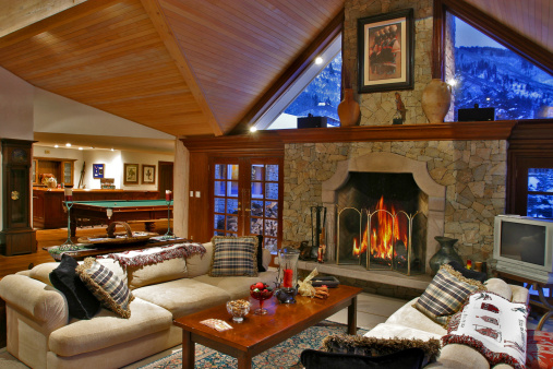 Luxurious mountain vacation home.  Interior of winter night with warm fire place inviting living room and great game room