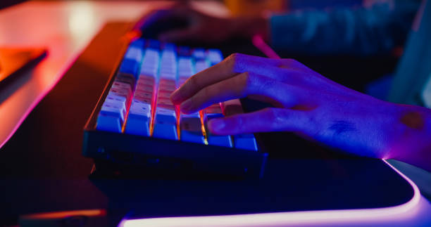 istock Close-up hands shot asia guy gamer use keyboard and mouse controller play video game with neon light computer in desk at home. 1399812485