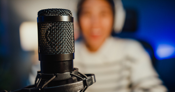 Happy asia lady blogger music influencer grabar un podcast en la computadora con auriculares y micrófono hablar con la audiencia en la sala de estar estudio en casa por la noche. photo