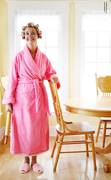 Woman posing in bathroom with rollers in her hair Woman wearing a pink robe and rollers in her dining room pink gown stock pictures, royalty-free photos & images