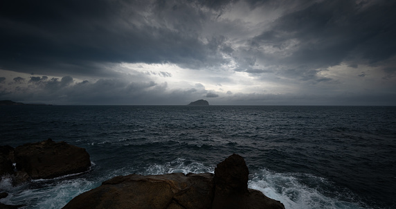 Cloudy day on the sea, sunlights shines between cloud, and a little island in the distances, in Keelung, Taiwan.