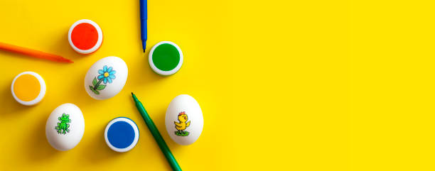 istock Hand painted easter eggs, paints and felt pens on yellow background. Top view, space for text. 1399819258