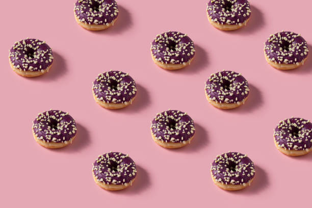 istock Donuts pattern image. Many Donuts with blueberry glaze and nuts  on pink background. 1399819342