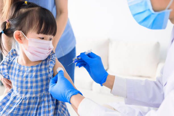 Medical Doctor injecting child with vaccine at clinic or hospital stock photo