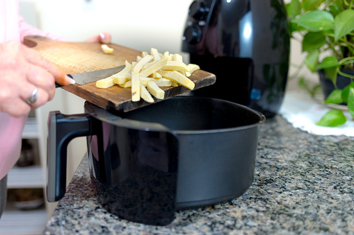 Putting sliced and frozen potatoes in the Airfryer for frying. Making healthy food without frying using oil.