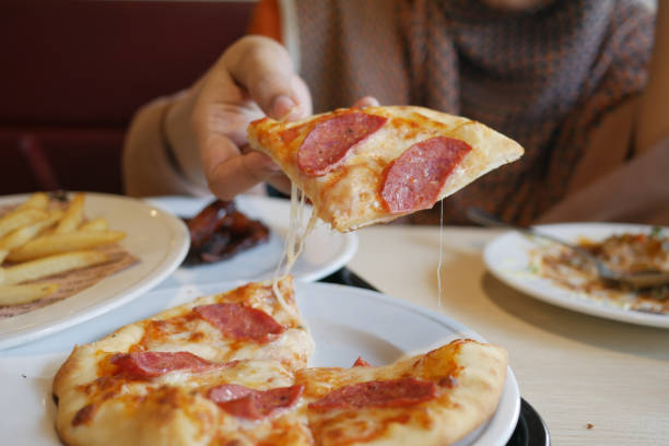 istock women hand picking slice of pizza from a plate 1399830706