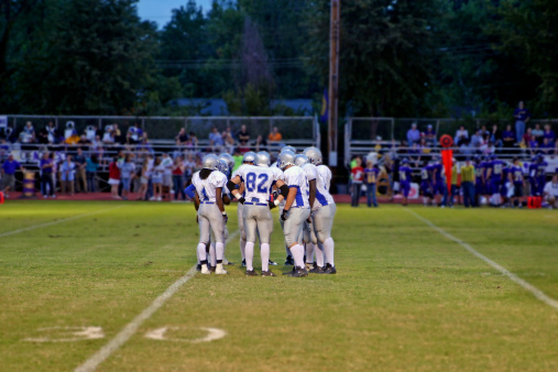 High School football team huddles around the QB
