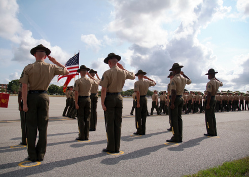 Dramatic shot of Drill Instructors saluting the U.S. flag during the graduation of recruits from US Marine Corps Recruit Depot, Parris Island, SC.