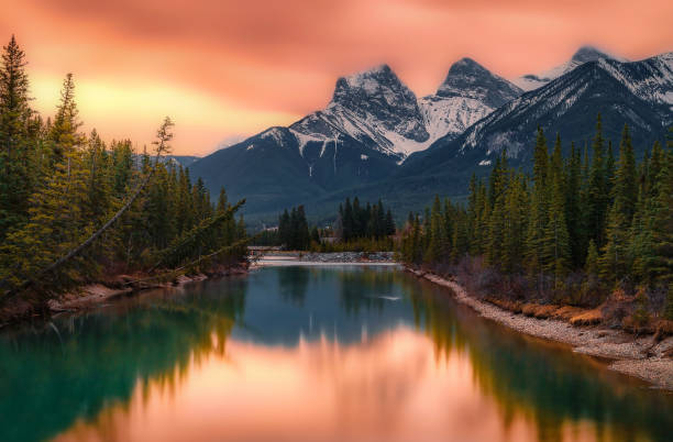 A bright orange sunrise glowing over the Three Sisters mountains in Canmore in the springtime.