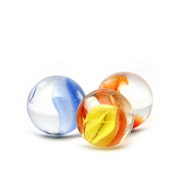 Three orange, blue and yellow glass marbles on white surface