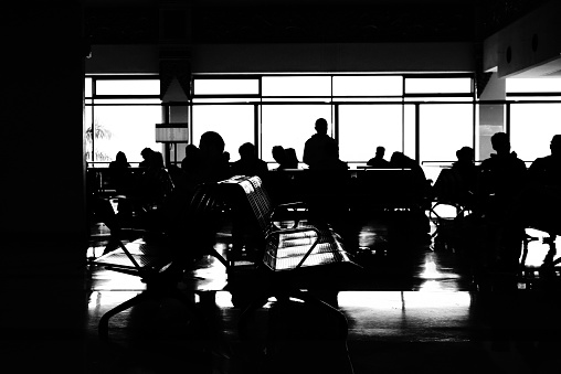 black and white abstract photo of people gathering and sitting in the waiting room