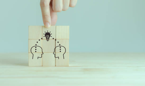 istock Knowledge and ideas sharing between two people head icon on wooden cube. Transferring knowledge, innovation, brainstorming concept. Business strategies to technology evolution reskill and new skill. 1399840008