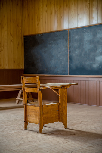 A single wooden desk and blackboard in an abandoned, rural one-room schoolhouse on the prairies in Saskatchewan