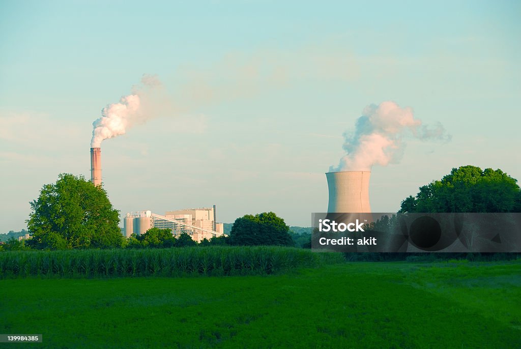 Power Plant Power plant with steam coming from the stacks, in the country behind a farmer's field. Agriculture Stock Photo
