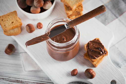 Little Toasts with sweet hazelnut chocolate spread for breakfast on white wooden background