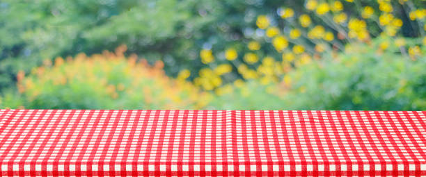 istock Empty table with red and white tablecloth over blurred park nature background, for product display montage, spring and summer 1399852654