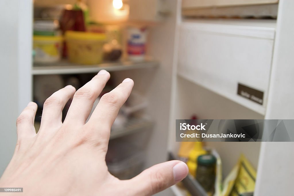 Hand reaching toward the refrigerator in hunger Hand reaching refrigerator Over Eating Stock Photo