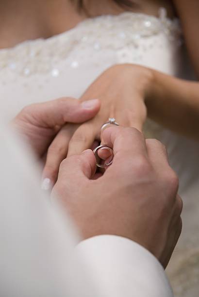 istock Bridegroom putting wedding ring on bride's finger 139985613