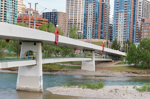 Large concrete structure red train bridge river in the middle clean with large buildings in the background growing city in canada pedestrian crossing under structure