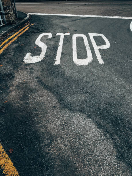 Stop sign painted on the asphalt of the parking lot in the city.  The stop sign has a black and white design