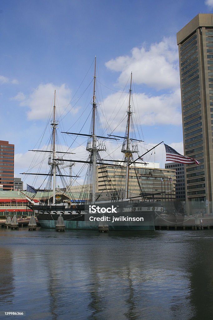 Tall ship - USS Constellation 1 Vertically-formatted view of the USS Constellation tall ship in the Baltimore Inner Harbor with flag flying and the world trade building looming over. Baltimore - Maryland Stock Photo