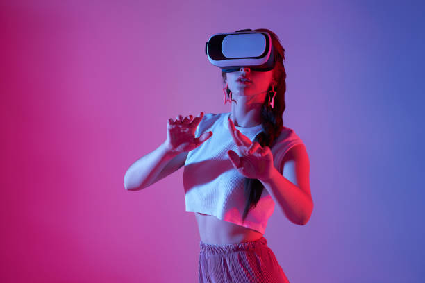 istock Amazed young woman using a virtual reality headset playing video games trying to touch something with hand. 1399864446
