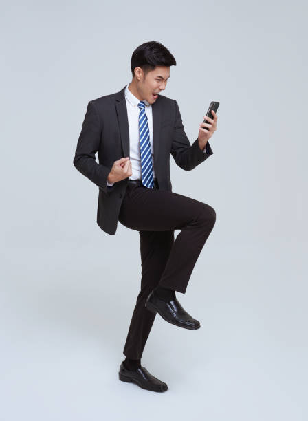 istock handsome Asian businessman using mobile phone and happy celebration isolated on studio white background. 1399864457