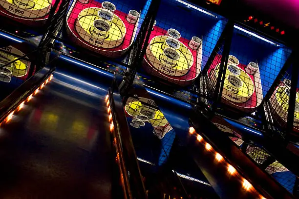 A series of skee-ball games lined up in an arcade.  Try to roll 100,000.