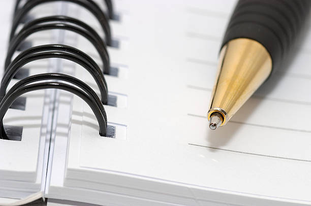 Empty blank ring, spiral notepad, gold pen closeup stock photo