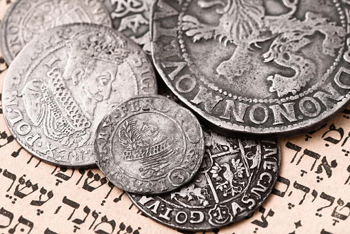 Pile of old silver coins on open Siddur page. Selective focus. Closeup