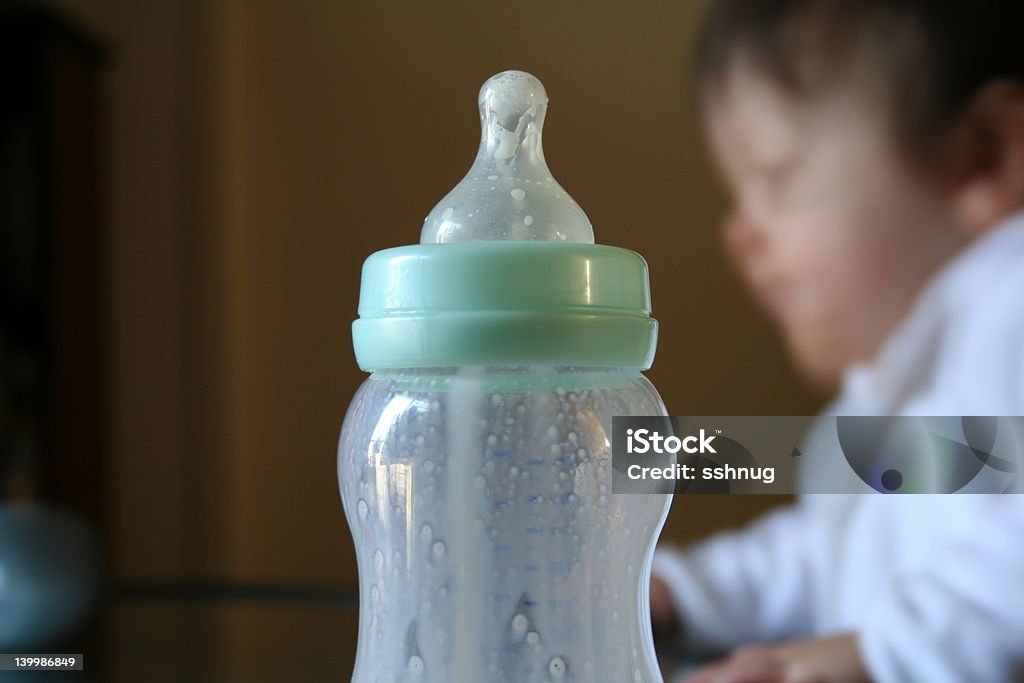 Babies Bottle 1 Babies bottle with blurred baby in background. Baby - Human Age Stock Photo