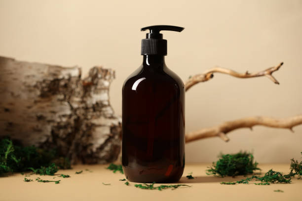 istock Dark pump dispenser bottle with natural shampoo. Tree branch, bark birch, moss on background. 1399869071