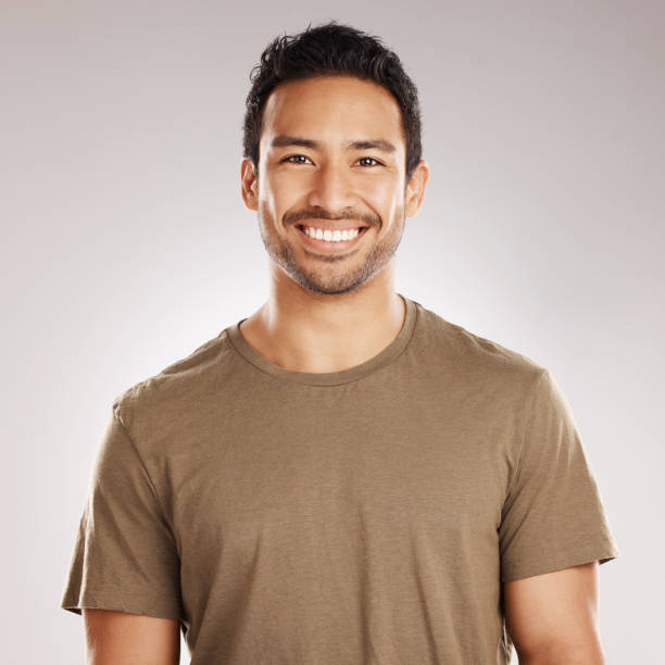 istock Handsome young mixed race man smiling and happy while standing in studio isolated against a grey background. Hispanic male in casual wear expressing happiness with a smile and looking at the camera 1399869345